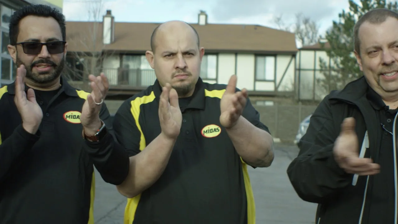 Midas team members in uniform applauding outside a shop